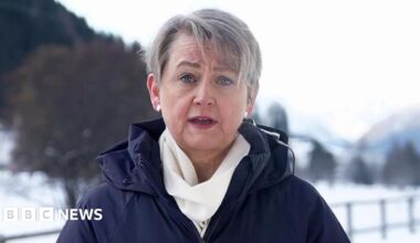 Yvette Cooper speaking to BBC Breakfast from Davos, in Switzerland dressed in a blue winter coat and white scarf, against a snowy backdrop