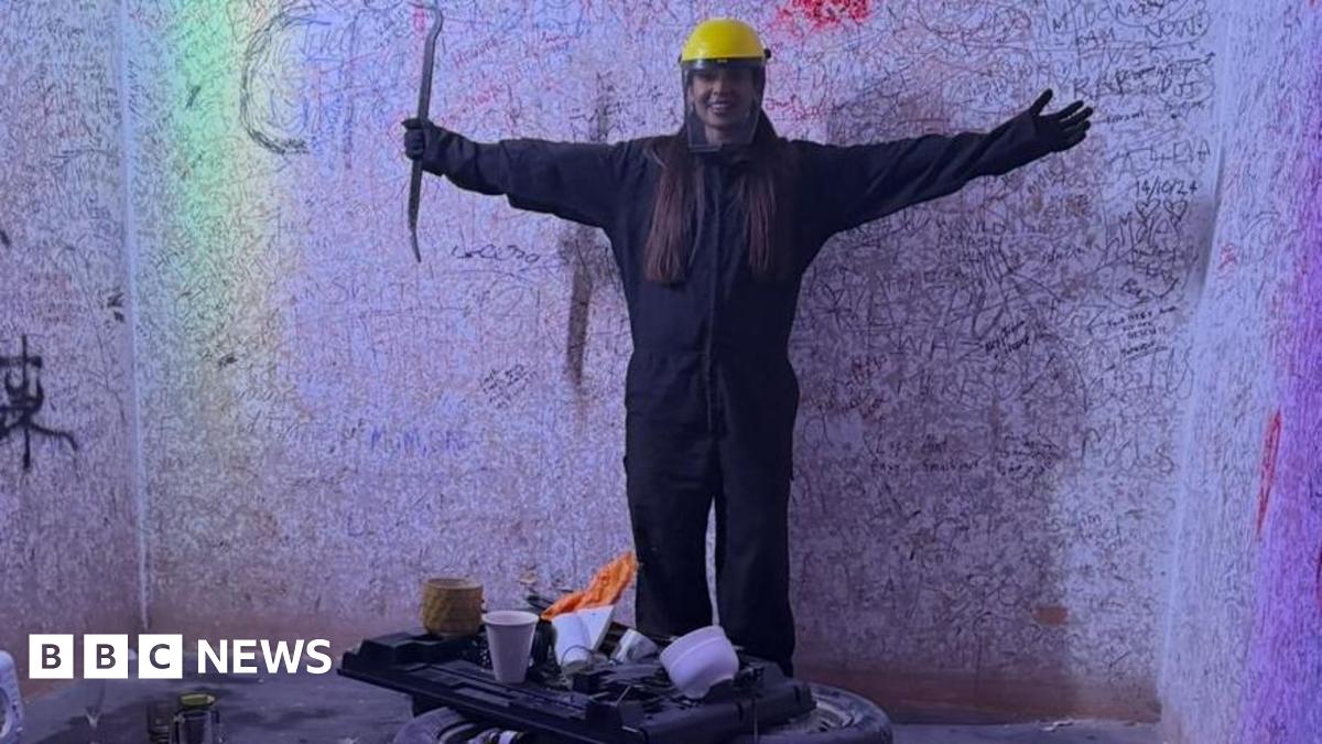 Picture of a woman in a rage room wearing protective clothing