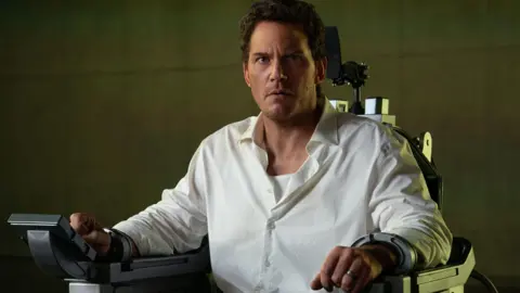 2025 Amazon Content Services LLC Chris Pratt locked in an executioner's chair, he's in a white shirt and looks very concerned