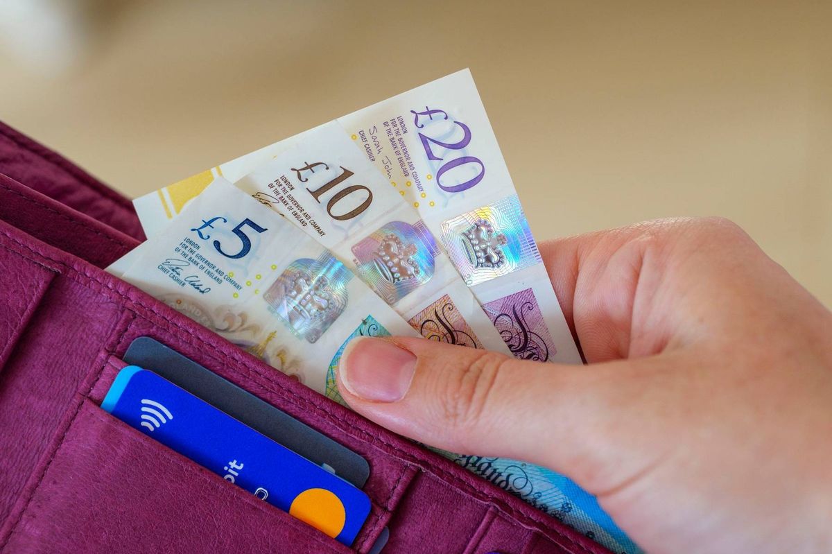Close up of hand taking out money as UK pound notes in cash from wallet