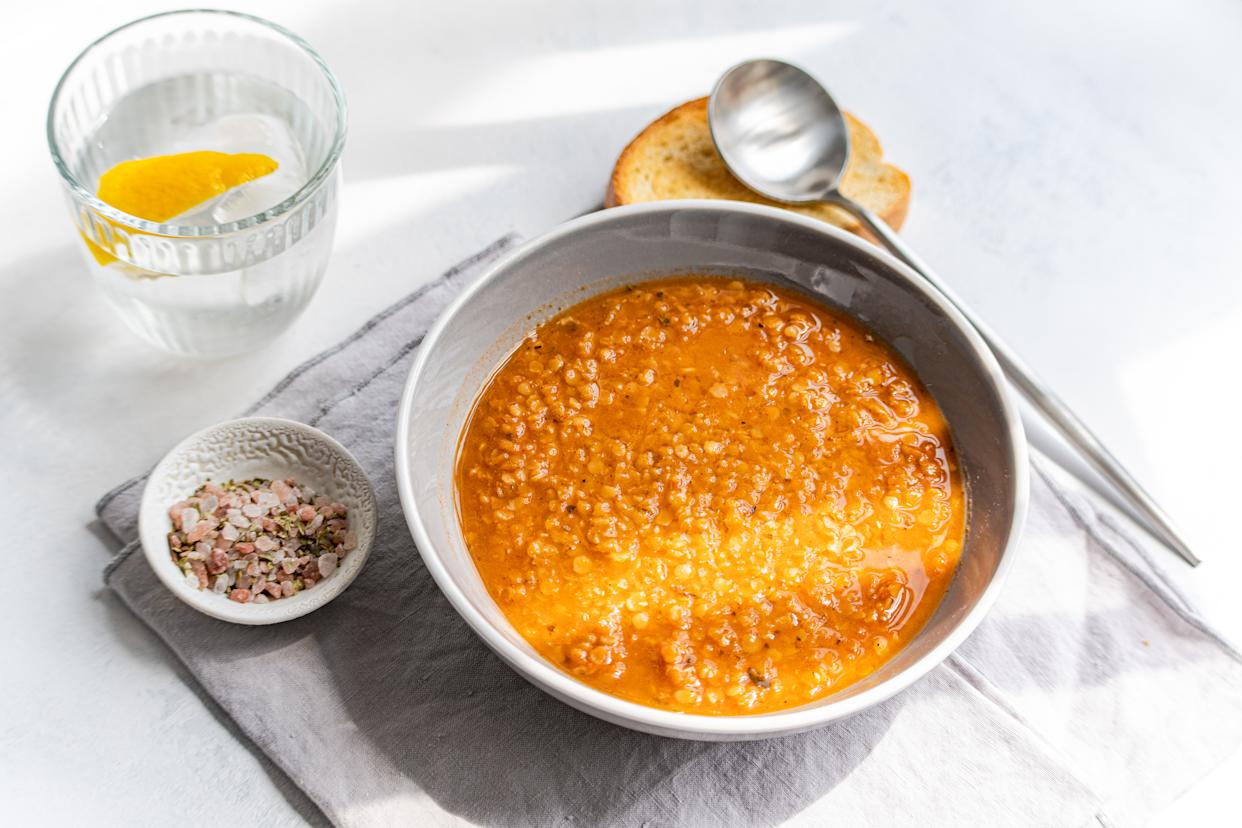 Overhead view of a bowl of Traditional Greek lentil soup (fakes) with toasted bread and a glass of lemon water