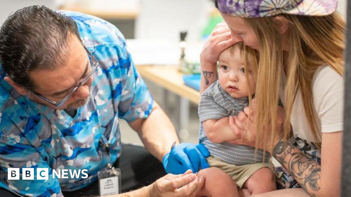 A one-year-old is held by his mother while he receives an MMR vaccine at a clinic in Texas