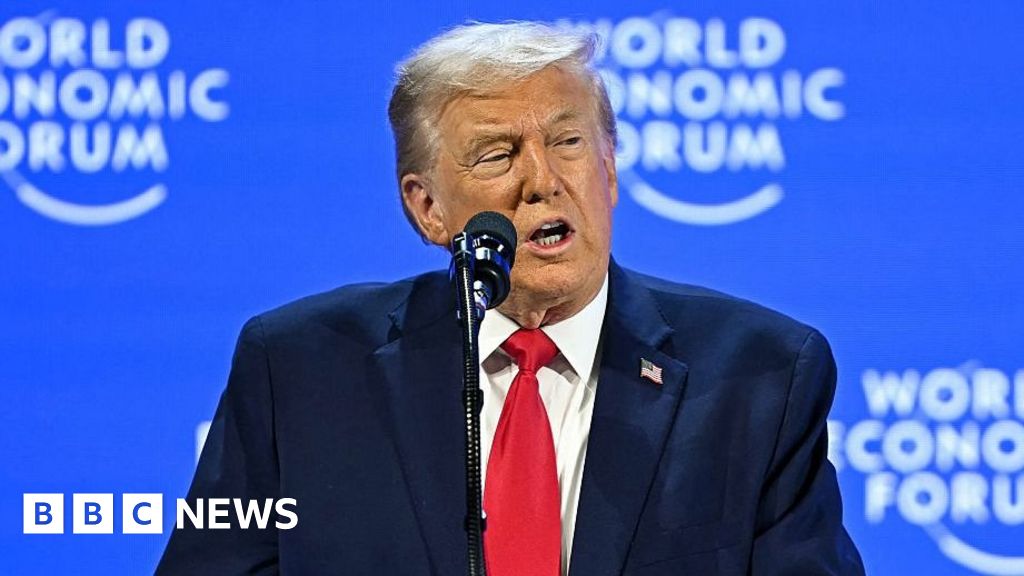 Trump in a red tie and blue jacket speaking at the world economic forum.
