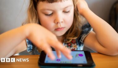 A young girl plays with a computer tablet on a table