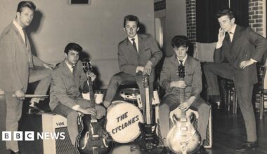Five young men photograhped in the 1950s wearing suits typical of that period. Two are holding guitars, one is standing over a drumkit with "The Cyclones" written on the front.