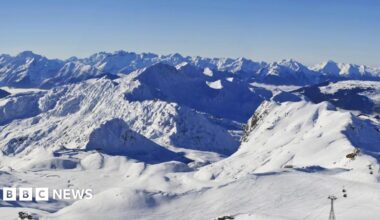 A white snowy mountainous landscape with a blue sky above is captured from the top of La Plagne ski resort in France.