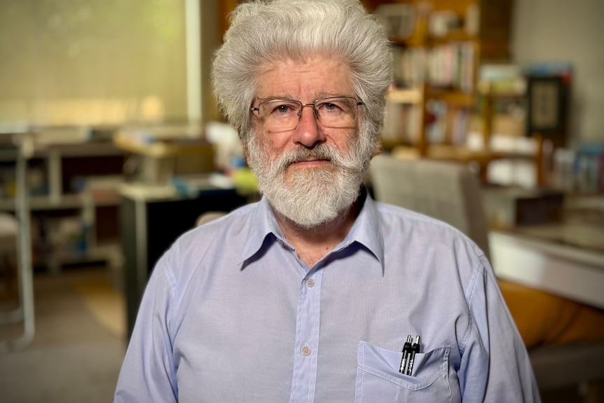 Man in a light blue shirt with clear framed glasses.