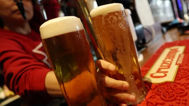 Two pints of foaming beer on a bar towel at a pub
