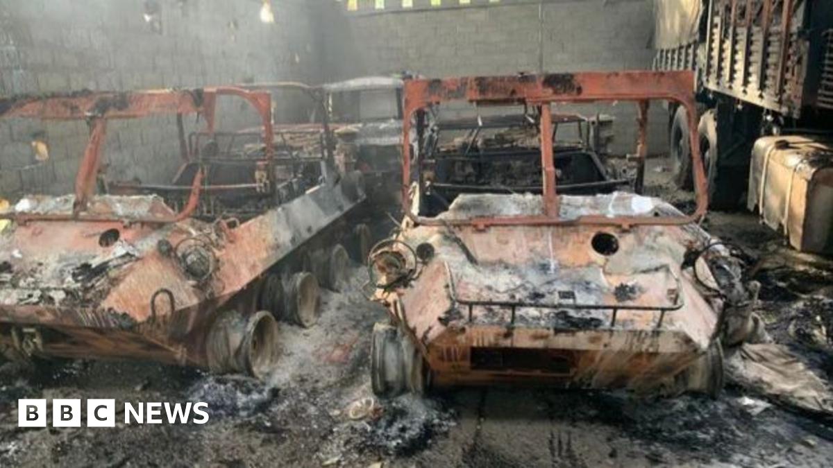 Maduro on the USS Iwo Jima, wearing a grey tracksuit and holding a bottle of water. He is blindfolded and wearing ear protection.
