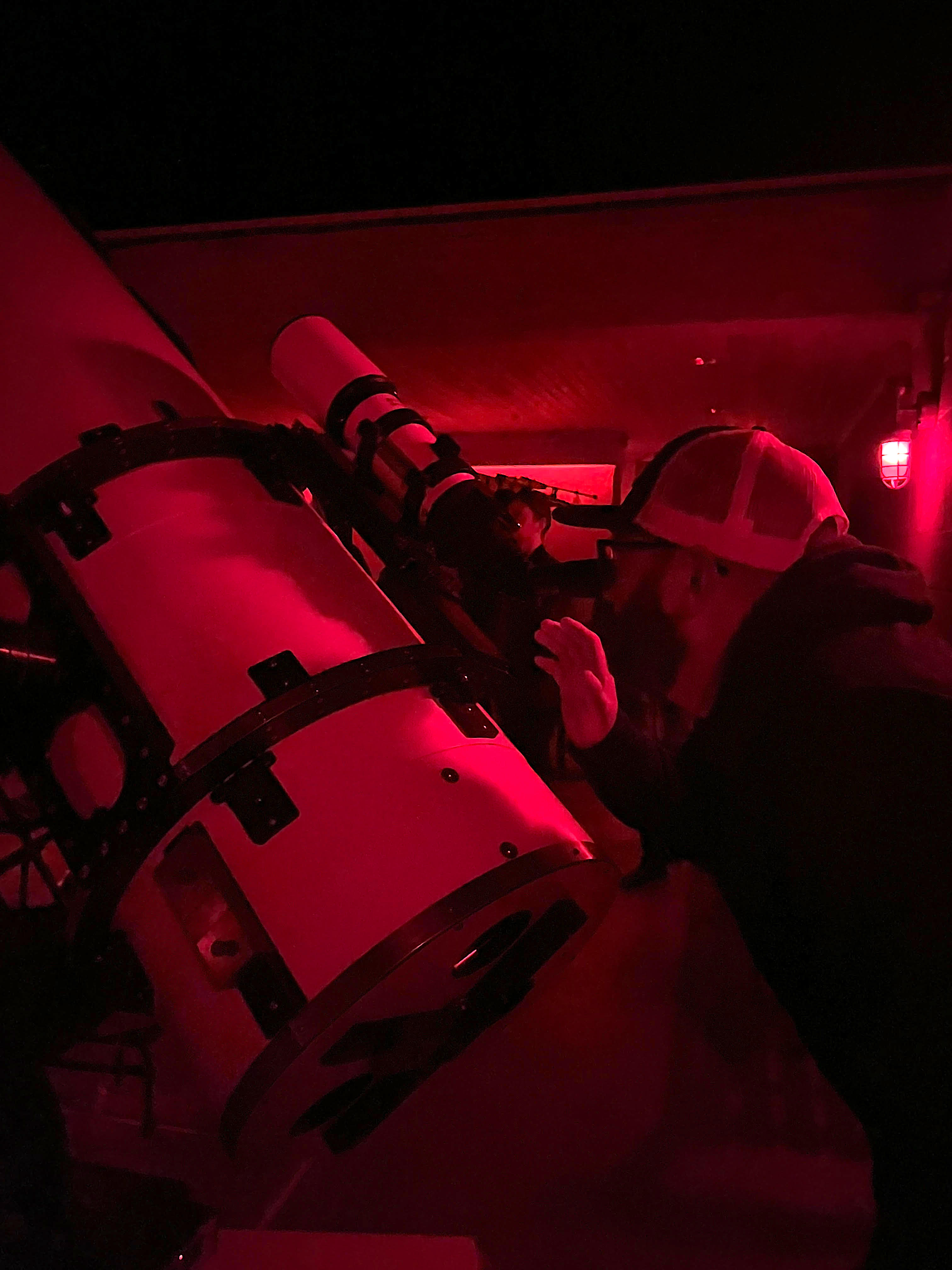 a man with a hat looking though a telescope