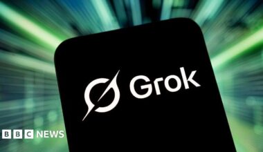 A phone with a black background and the white Grok logo on it. It is against a bright green background.