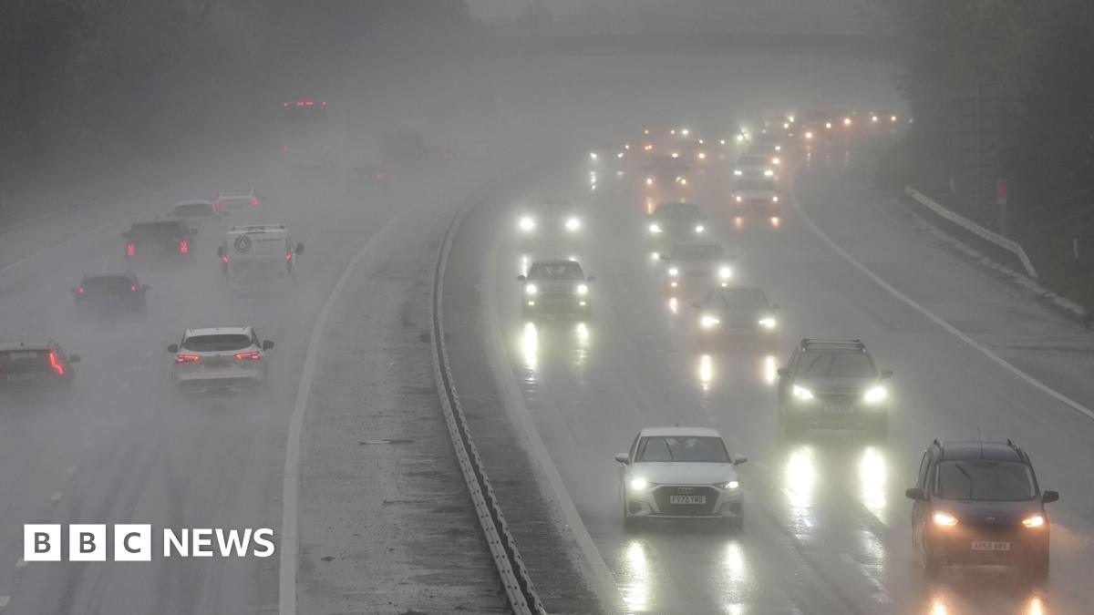 Surface water on a motorway with cars driving on it. The water is causing a glare from car headlights.