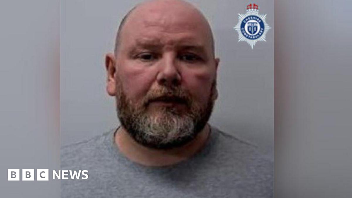 Police custody image of Kieran Cameron. He has a beard and is wearing a grey sweatshirt.