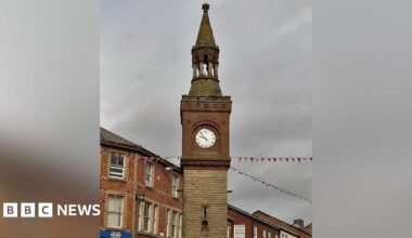 View of the top of the historic Ormskirk Clock Tower on a grey cloudy day.