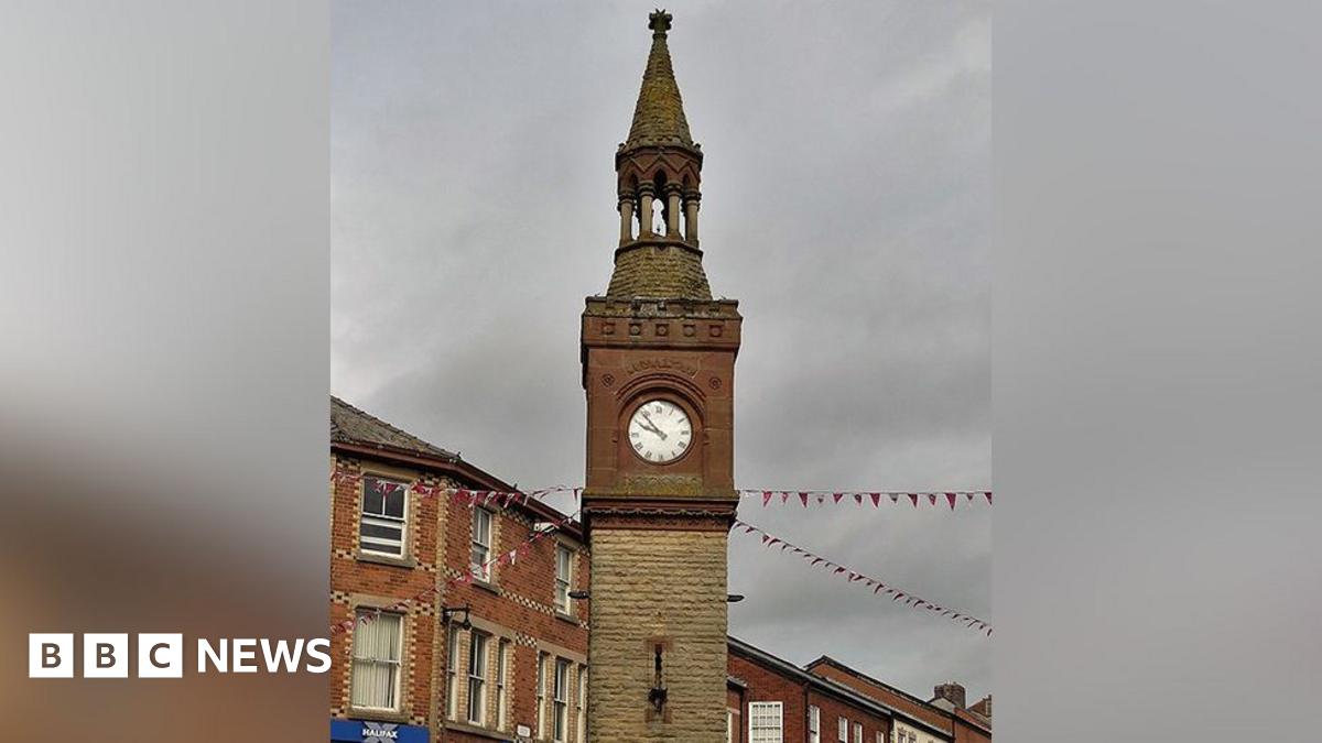 View of the top of the historic Ormskirk Clock Tower on a grey cloudy day.