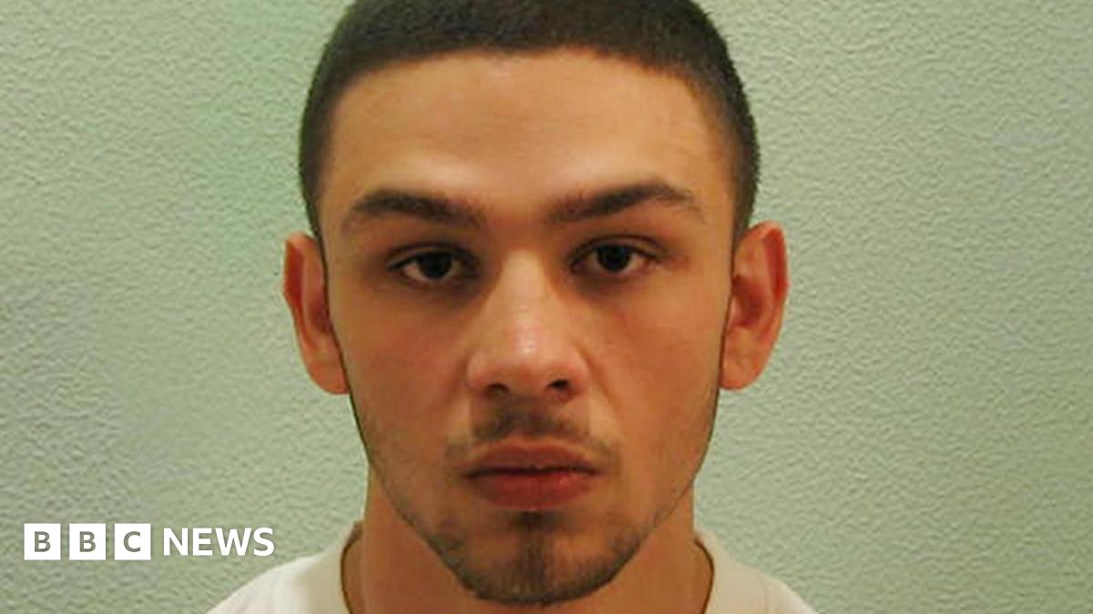 A custody photo of Jake Fahri. He has short brown hair, a moustache and short beard.