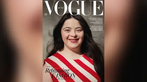 Adama Jalloh/British Vogue Ellie in a red and white striped dress on the cover of Vogue. She is looking into the camera and smiling
