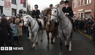 Riders with their hard hats and hunting outfits from The Holcombe Harriers hunt ride through the streets of  Wheelton, Lancashire opposdite the RTed Lion Inn.