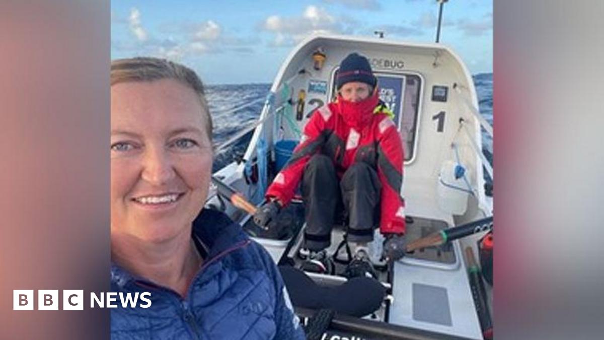 Emma Wolstenholme and a crew member on board their small rowing boat. She is in blue while her colleague wears a red overcoat and beanie hat