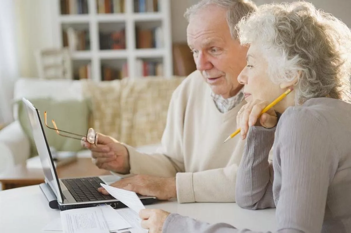 An older man and woman are sitting together looking at a computer screen.