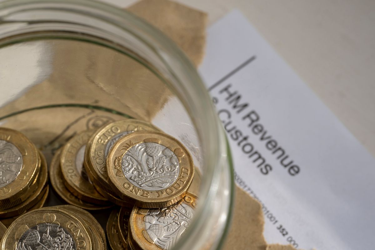 HMRC opening a tax letter with a jar of pound coins for payment.