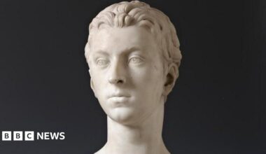 The bust is made from marble and shows the head of a young man, Sir John Gordon. The sculpture is photographed against a black background.