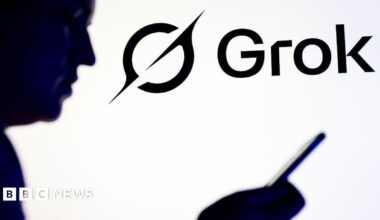 The logo of Grok in the background alongside a silhouette of a man holding and looking at a mobile phone.