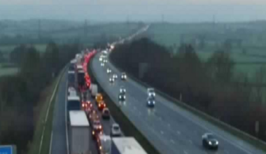 A woman wearing a dark hijab and black dress walks past a mural on a wall depicting politicians from the US and Iran sitting opposite each other, taken in Tehran on 28 January.