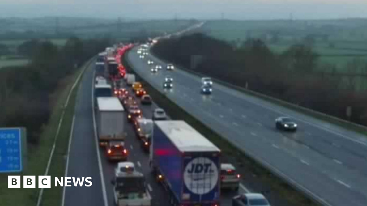 A woman wearing a dark hijab and black dress walks past a mural on a wall depicting politicians from the US and Iran sitting opposite each other, taken in Tehran on 28 January.