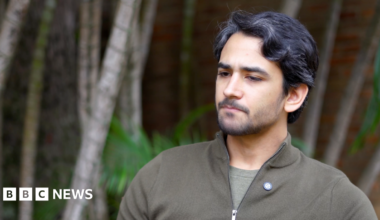A group of women, most wearing T-shirts and jeans, stand outside El Helicoide prison holding signs