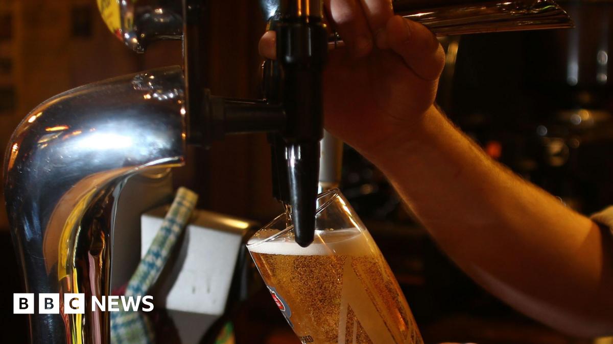 A close-up of a person pouring a pint on tap.