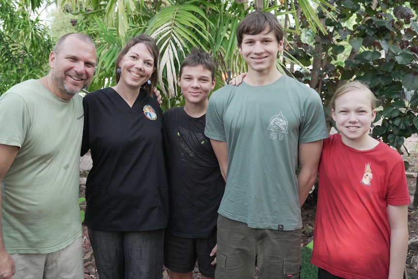 A married couple standing with their three sons, all of them are smiling at the camera.