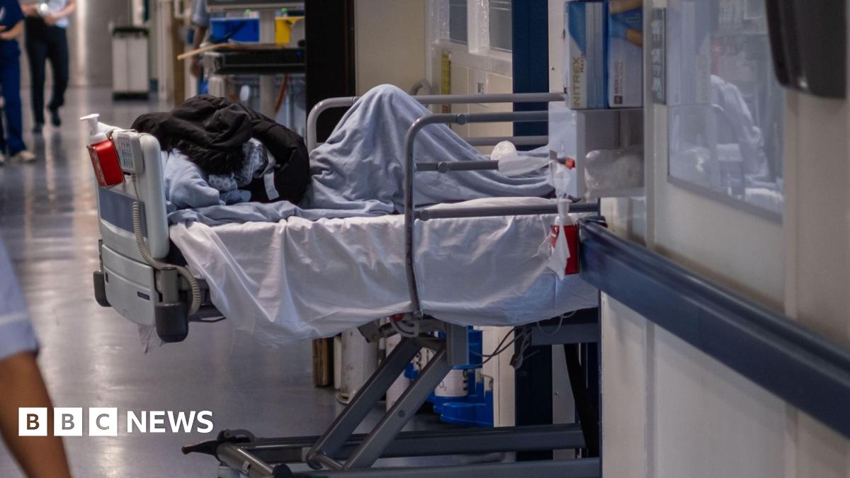 A patient bed is being pulled through a doorway on an NHS hospital ward.