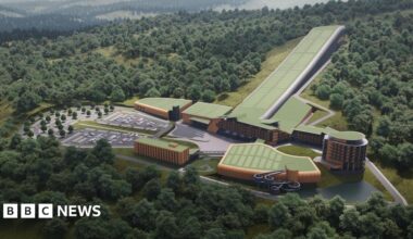 A computer generated picture showing a number of large buildings set into the side of a hill with trees.  One of the buildings is very long and narrow in shape and sloped down the hillside.