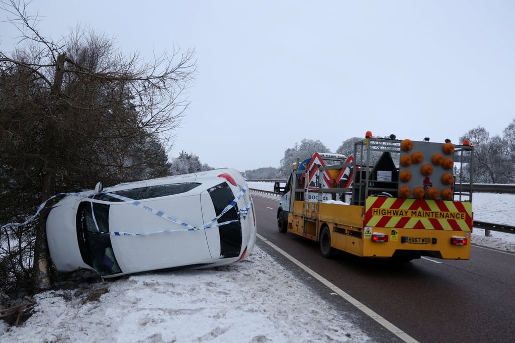 A highway maintenance vehicle drives on the A9 road, as a crashed vehicle lies on its side near Aviemore on Friday, with Scotland in the grip of a deep freeze following Storm Goretti. Photo: Reuters