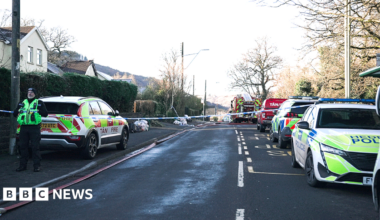 A police cordon has been put across a residential road, with emergency services vehicles parked at the scene
