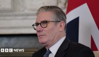 Keir Starmer wearing a suit in front of a union flag. He is looking into the distance