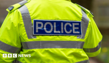 The back of a police officer wearing a yellow high vis jacket