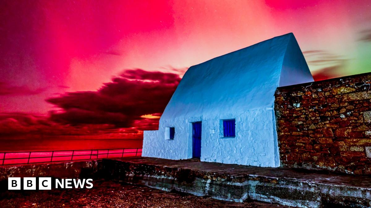 Donald Trump and Keir Starmer sit in a formal drawing room setting  on arm chairs with US and UK  flags behind them. Both have serious expressions and are looking out and not at each other.