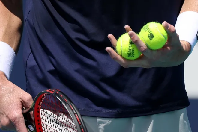 Mar 28, 2021; Miami, Florida, USA; John Isner of the United States holds four balls in his hand prior to serving against Felix Auger-Aliassime of Canada (not pictured) in the third round in the Miami Open at Hard Rock Stadium.