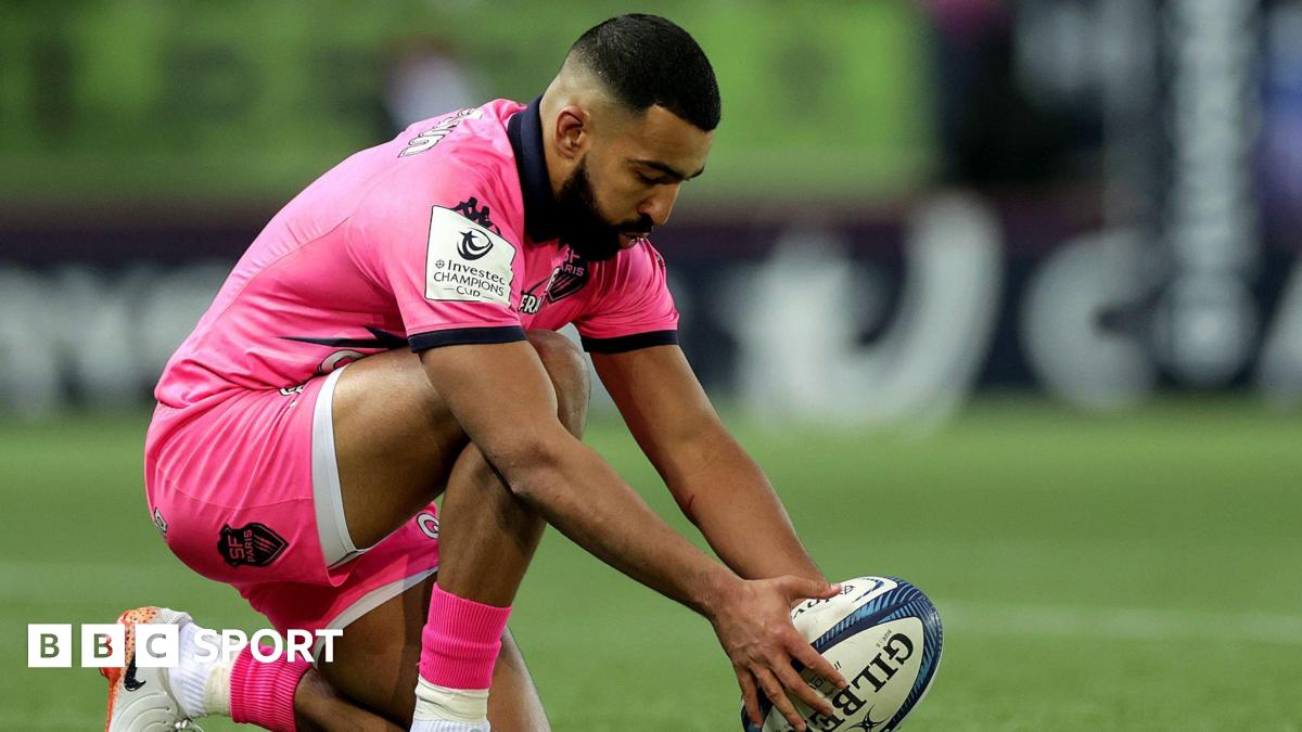 Zack Henry placing the rugby ball down on a tee ready for a kick at goal while dressed in Stade Francais' all-pink kit