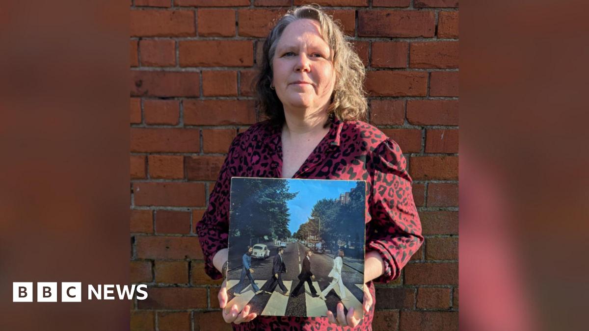 Emma Bowden holding a copy of Abbey Road by The Beatles on vinyl.