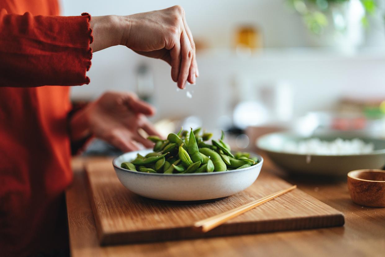 An anonymous chef preparing edamame beans in a kitchen.
