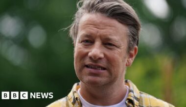 Jamie Oliver - head and shoulder image. He is wearing a yellow and grey checked shirt.