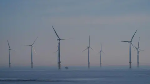 Getty Images Several wind turbines in the blue sea, with a grey-blue sky