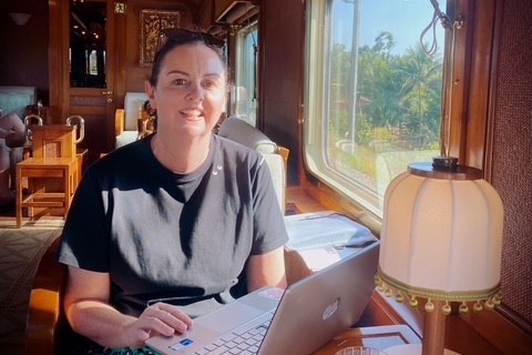 A woman on a train working on a laptop