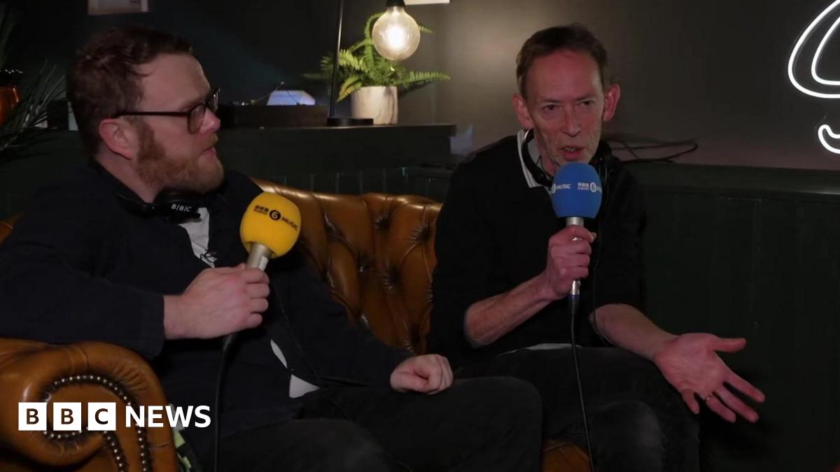 Huw Stephens and Steve Lamacq sit on a sofa at the venue holding 6 Music microphones.