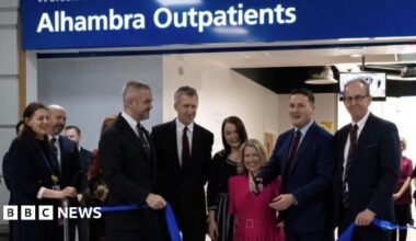 An image of a ribbon cutting service at the entrance to the outpatients service.  Health Secretary Wes Streeting is pictured with scissors in his hand alongside Barnsley council leader Sir Steve Houghton, local MPs Marie Tidball, Dan Jarvis and Stephanie Peacock and South Yorkshire Mayor Oliver Coppard.
