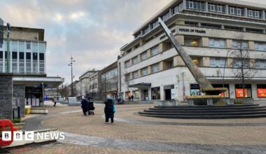 A general view of Plymouth City Centre. The sundial is on the right and there's people stood nearby. The toilet blocks are to the left.