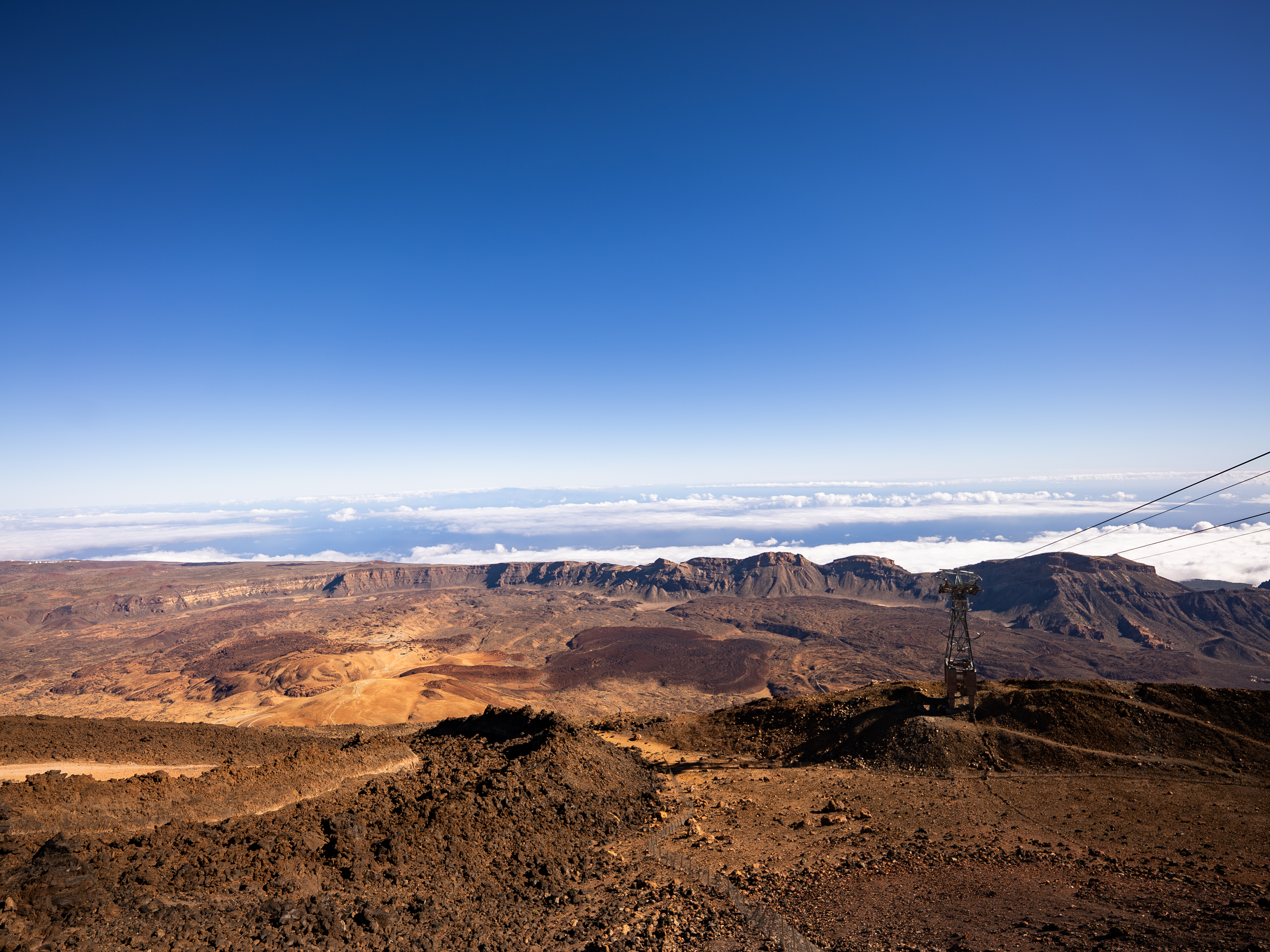 a vast rocky expanse looks like the surface of mars with blue sky above and clouds below.